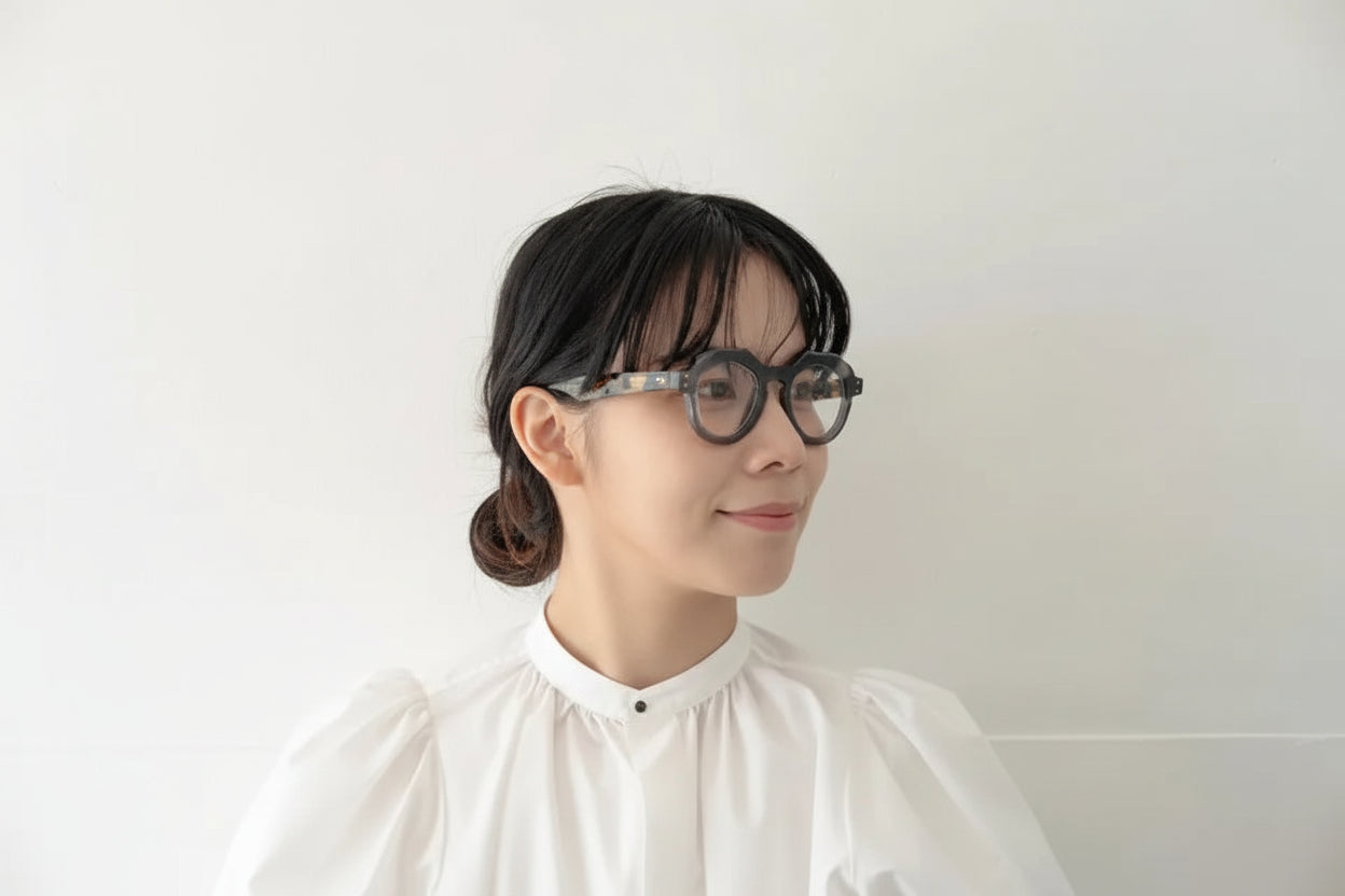 Person wearing glasses and a white shirt against a plain background