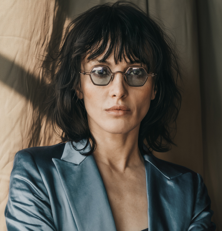 Woman wearing glasses and a blue jacket against a neutral background